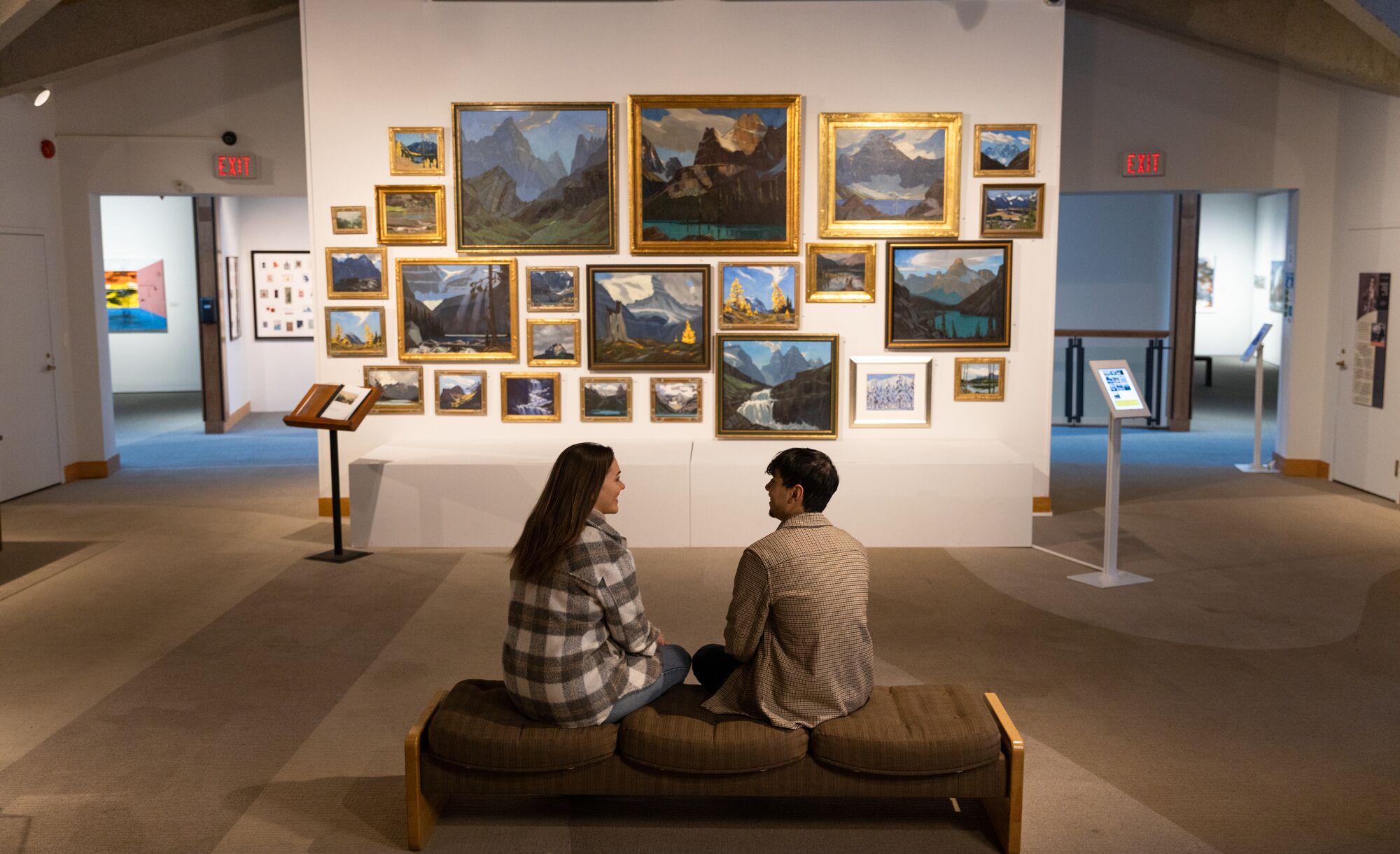 Two people sit on a bench in front of an art gallery in the Whyte Museum.